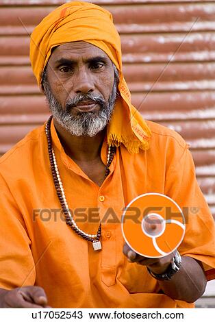 Stock Image - Close-up of a mature man holding a cd, Pushkar, Rajasthan, India. Fotosearch