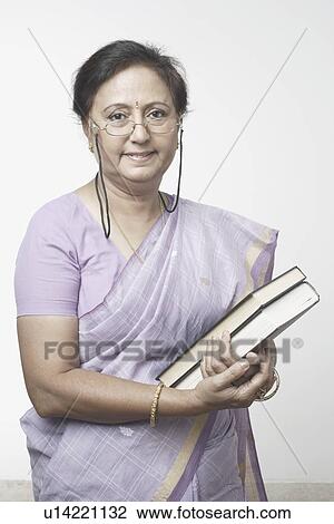 Stock Image - Portrait of a female professor holding books. Fotosearch