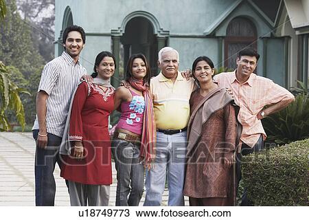 Stock Image - Portrait of a mature couple and their four children standing in front of a house. Fotosearch