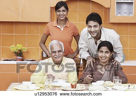 Stock Photograph - Portrait of a mature couple and their two children at the dinning table. Fotosearch