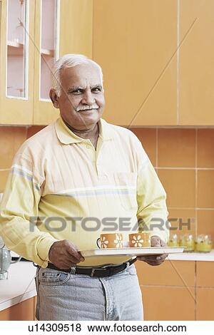 Portrait of a mature man holding a tray with tea cups View Large Photo Image Stock Photo - Portrait of a mature man holding a tray with tea cups. Fotosearch