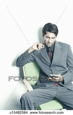 Picture - Businessman using a personal data assistant. Fotosearch