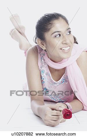 Stock Image - Close-up of a young woman lying down holding a flower. Fotosearch