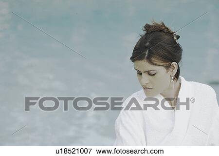 Stock Photo - Close-up of a young woman with a facial mask standing at the poolside. Fotosearch