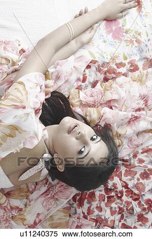 High angle view of a young woman lying on the bed View Large Photo Image Stock Photography - High angle view of a young woman lying on the bed. Fotosearch