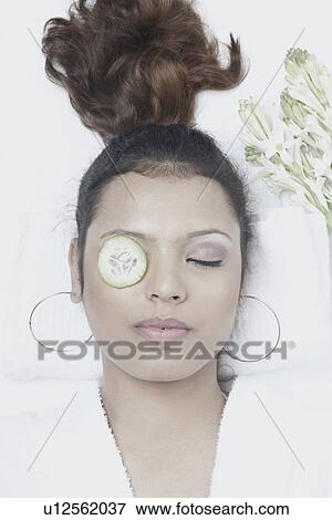 High angle view of a young woman with a cucumber slice on her eye View Large Photo Image Stock Photo - High angle view of a young woman with a cucumber slice on her eye. Fotosearch