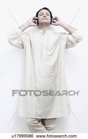 Stock Photograph - Mid adult man wearing headphones listening to music. Fotosearch