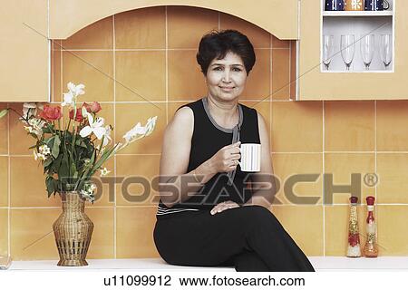 Stock Image - Portrait of a mature woman holding a mug. Fotosearch