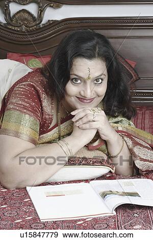 Stock Photo - Portrait of a mature woman with her hand under her chin lying on the bed. Fotosearch