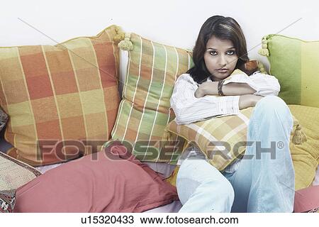 Stock Image - Portrait of a young woman hugging a cushion. Fotosearch