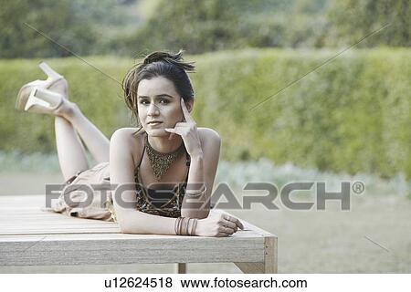 Portrait of a young woman lying on a bench View Large Photo Image Stock Photo - Portrait of a young woman lying on a bench. Fotosearch