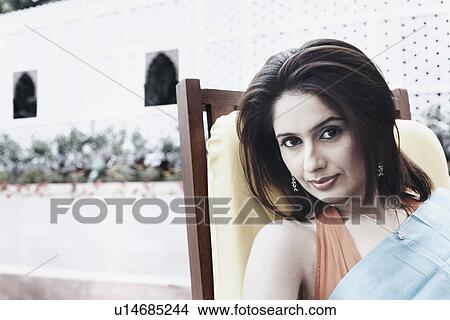 Picture - Portrait of a young woman sitting on an outdoor chair. Fotosearch