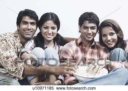 Portrait of two young couples sitting together on a couch and eating popcorn View Large Photo Image Stock Photography - Portrait of two young couples sitting together on a couch and eating popcorn. Fotosearch