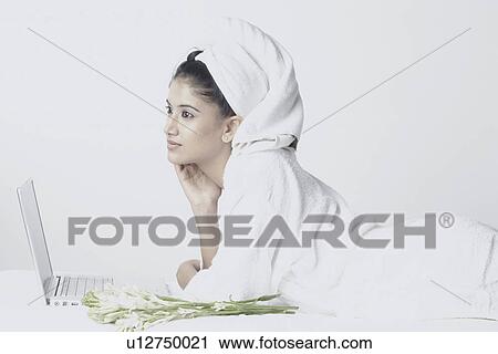 Side profile of a young woman lying in front of a laptop View Large Photo Image Stock Image - Side profile of a young woman lying in front of a laptop. Fotosearch