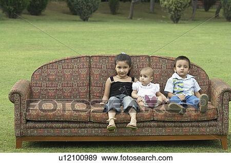 Stock Photo - Three children sitting on a couch outdoors. Fotosearch
