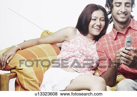 Stock Photo - Young couple looking at a mobile phone. Fotosearch