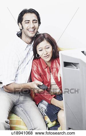 Stock Photo - Young couple watching television. Fotosearch
