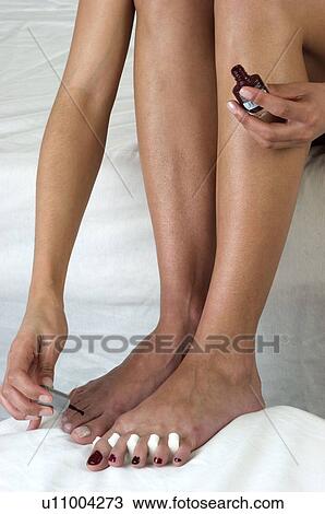 Stock Image - Woman, Beauty, Bodycare, Sitting, Bed, Nail polish, Painting. Fotosearch