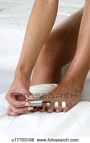 Stock Photo - Woman, Beauty, Bodycare, Sitting, Bed, Nail polish, Painting. Fotosearch