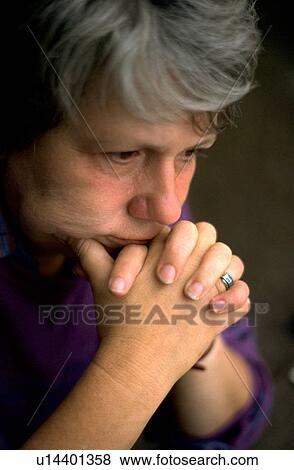 Stock Photo - Woman deep in thought with chin in her folded hands. Fotosearch