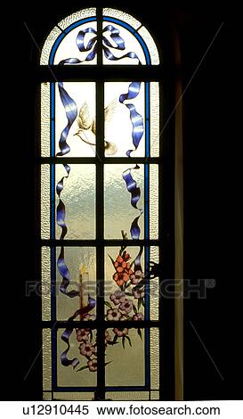 Stock Photography - Dove candle ribbons and flowers on stained glass. Fotosearch