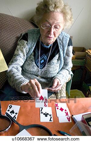 Stock Photo - Aunt Fran age 92 playing solitaire with large print cards suffering from macular degeneration. Fotosearch