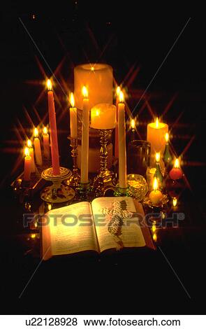 Stock Photo - Candles surrounding open Bible with a cross on the pages. Fotosearch