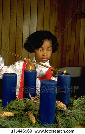 Stock Photo - Girl lighting Christmas Advent candles in church. Fotosearch