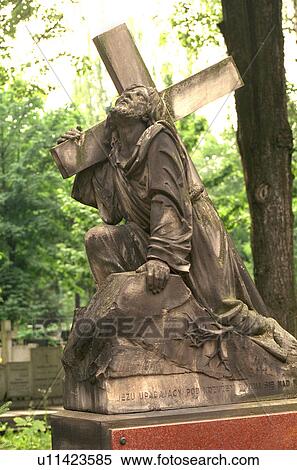 Stock Photography - Grave with stone carving of Jesus with cross praying to heaven. Fotosearch