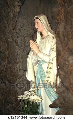 Picture - Statue of Mother Mary praying with flowers at feet. Fotosearch