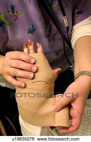 Stock Photograph - Emergency room nurse wrapping temporary elastic bandage on broken wrist. Fotosearch