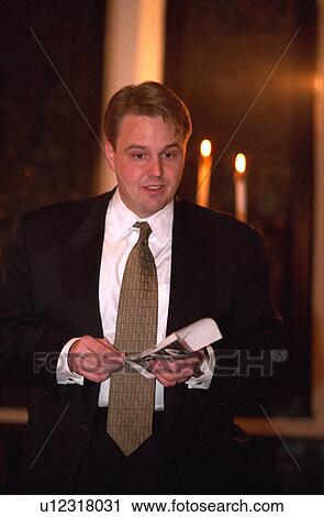 Stock Image - Father age 30 reading poem at sons baptism. Fotosearch