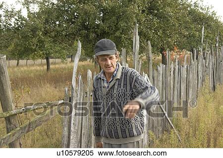 Stock Photography - Polish farmer working on his fence. Fotosearch