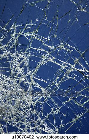 Stock Image - Cracked glass against blue background.. Fotosearch