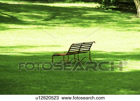 Stock Image - A park bench on green grass. Fotosearch