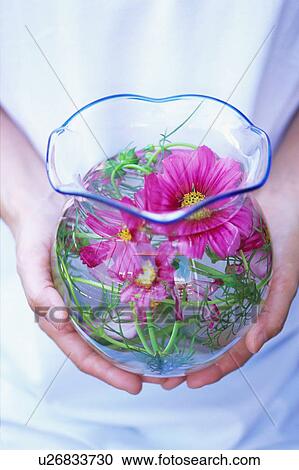 Stock Image - A woman holding flower bouquet in vase. Fotosearch