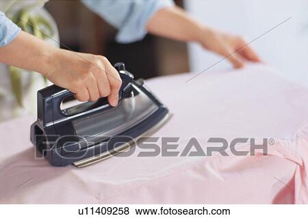 Stock Photo - Mid adult woman ironing, close-up. Fotosearch