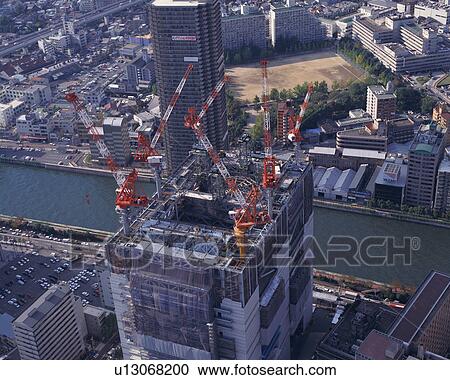 Stock Image - Aerial view of cranes on the top of a skyscraper. Fotosearch