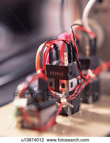 Stock Image - Red wires are attached to electronic devices. Fotosearch