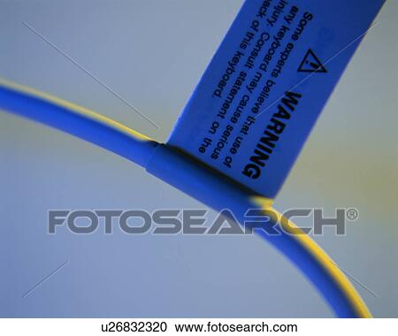 Stock Image - Side view of a warning tag on keyboard cable. Fotosearch