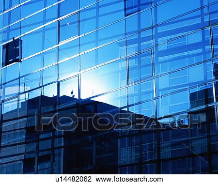 Stock Image - Sky and buildings reflected into the glass building. Fotosearch