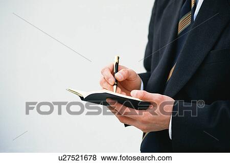 A businessman taking down notes in his personal diary View Large Photo Image Stock Photo - A businessman taking down notes in his personal diary. Fotosearch