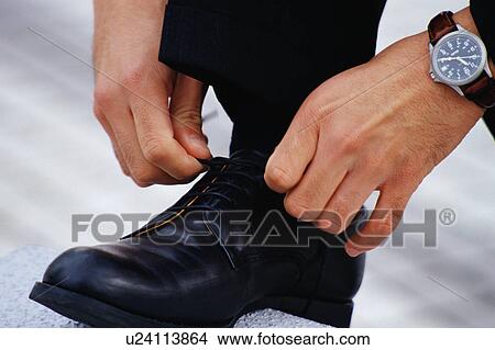 Picture - Close up of a man tying his shoe lace. Fotosearch