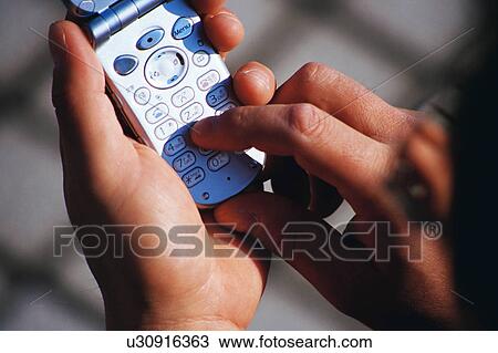 Stock Image - Close up of a person dialing a number from his cell phone. Fotosearch