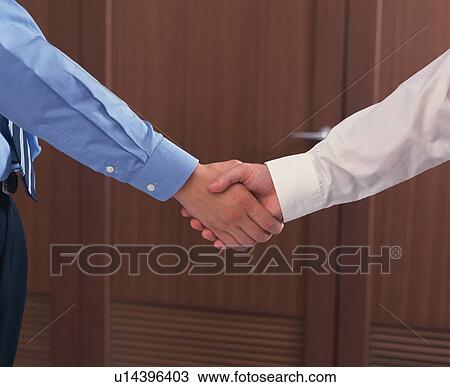 Stock Image - Close up of two businessmen shaking hands. Fotosearch