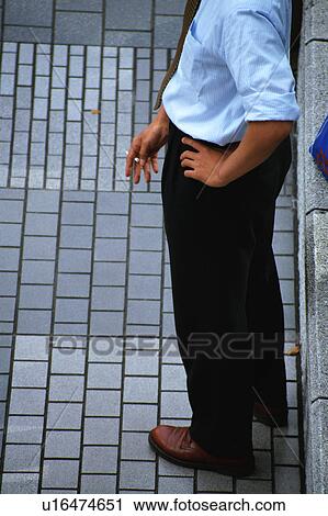 Stock Image - High angle view of a man holding a cigarette. Fotosearch