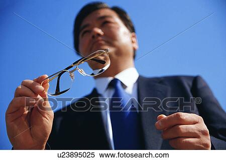 Low angle view of a mature man holding spectacles View Large Photo Image Stock Photography - Low angle view of a mature man holding spectacles. Fotosearch