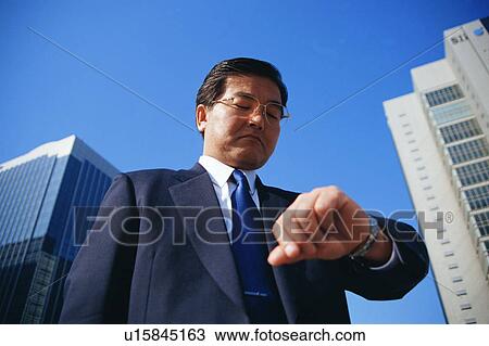 Low angle view of a mature man looking at his wrist watch View Large Photo Image Stock Image - Low angle view of a mature man looking at his wrist watch. Fotosearch