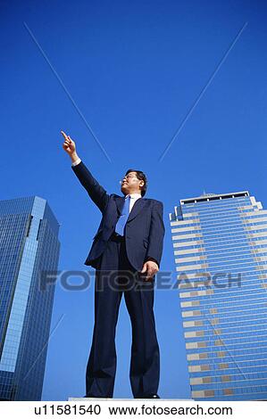 Stock Image - Low angle view of a mature man pointing towards sky . Fotosearch