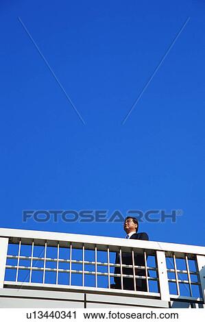 Stock Image - Low angle view of a mature man standing near railing. Fotosearch